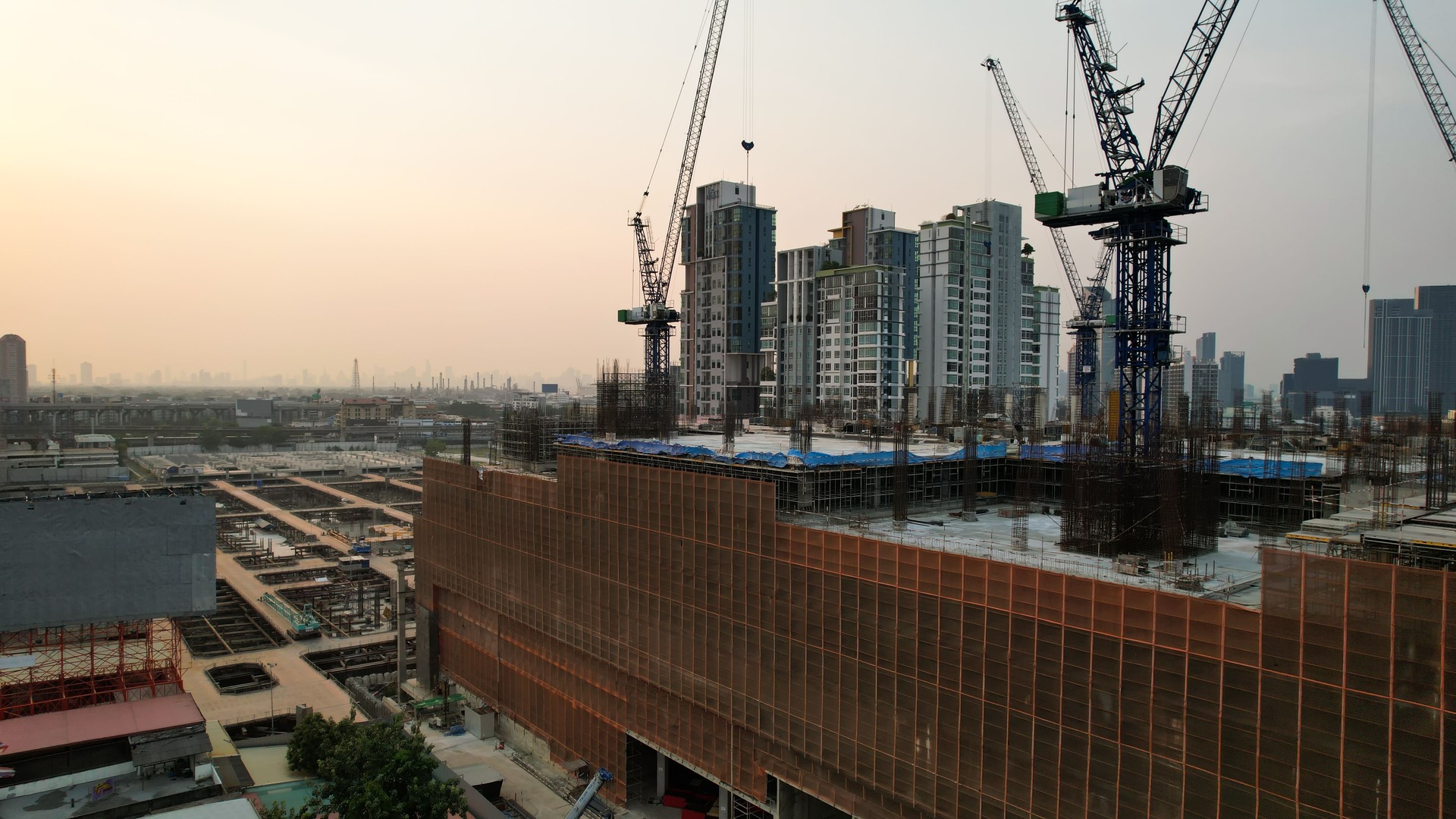 Power crane and new construction high building, New construction site with cranes on orange sunset, sunrise sky background. Steel frame structures and structural steel beams build large buildings at the construction site. construction machinery.
